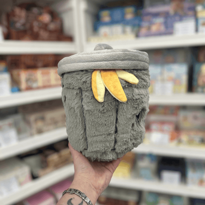 Mini Squishable Trash Can plush toy held in hand in a gift shop, back view with banana peel detail