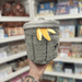 Mini Squishable Trash Can plush toy held in hand in a gift shop, back view with banana peel detail