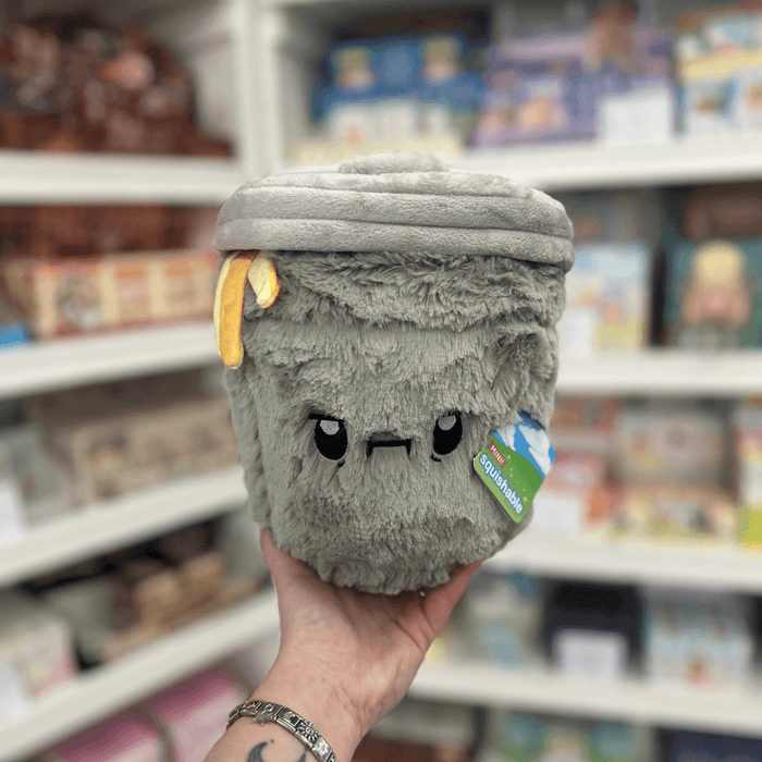 Mini Squishable Trash Can plush toy held in hand in a gift shop, front view
