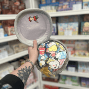 Mini Squishable Trash Can plush toy opened to reveal illustrated rubbish inside, held in hand in a gift shop