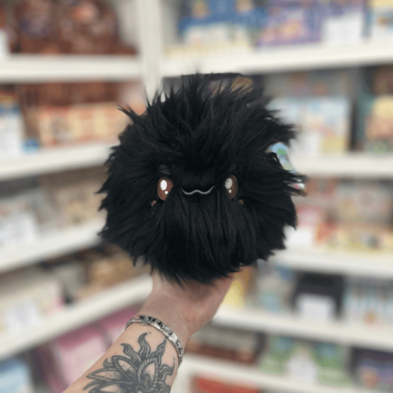 Mini Squishable Woolly Caterpillar plush held in hand in a gift shop, front view