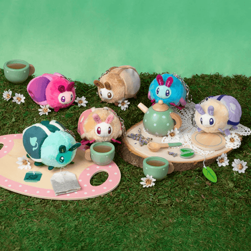 Squishable Cup of Tea moth plush keychains arranged around a miniature tea party