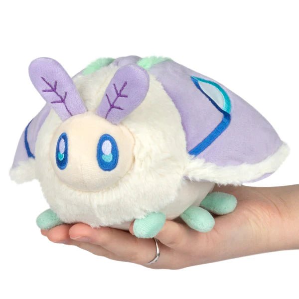 Squishable Party Snacker Lilac Luna Moth plush with lilac wings, mint trim and blue eyes, held in hand