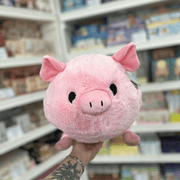 Squishable Piggy pink plush toy held in a gift shop, showing its round fluffy body, soft ears and cute snout