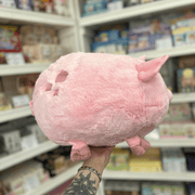 Squishable Piggy plush toy side view with soft pink fur, little legs and cute rounded shape in a shop setting