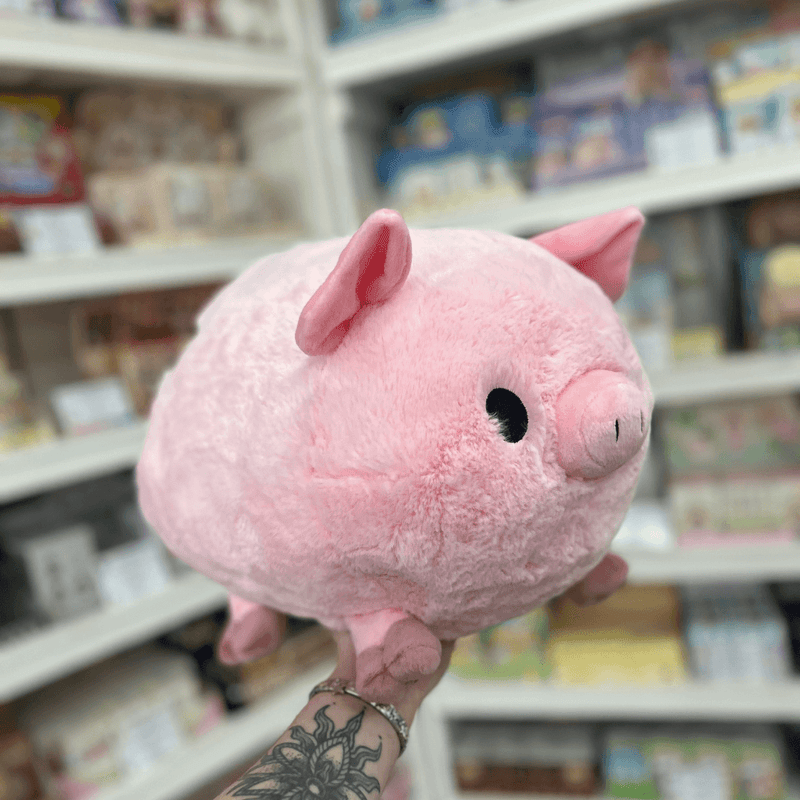 Side view of Squishable Piggy plushie with soft pink fur, floppy ears and rounded pig design