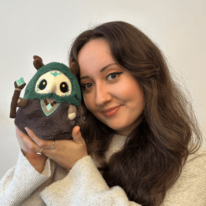 Person holding Squishable Plague Doctor Forest Queen plush with green hood and staff