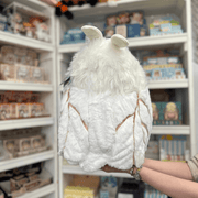 Squishable Poodle Moth plush toy held in hands in a gift shop, back view showing wings