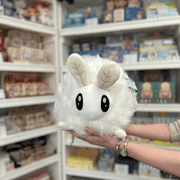 Squishable Poodle Moth plush toy held in hands in a gift shop, front view