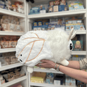 Squishable Poodle Moth plush toy held in hands in a gift shop, side view showing wing detail