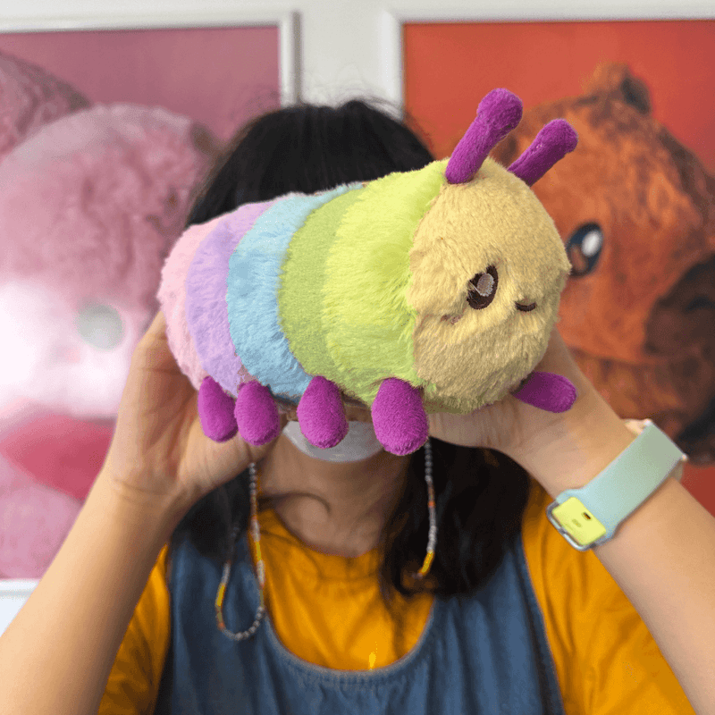 Squishable Snacker Rainbow Caterpillar plush being held