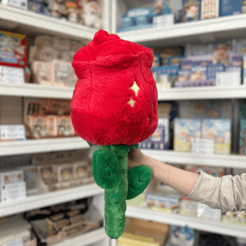 Squishable Red Rose plush toy side back view held in hand in a shop