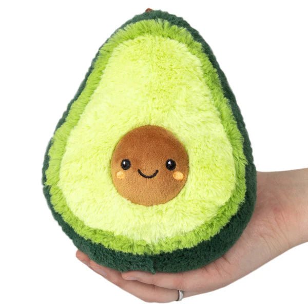 Front view of the Squishable Snacker Avocado plushie showing a cute smiling pit and fuzzy green layers.