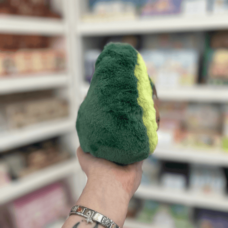 Squishable Snacker Avocado plush toy held in hand, side view