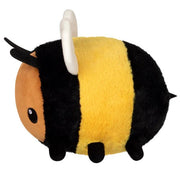 Side view of the Squishable Snacker Fuzzy Bumblebee plushie with yellow and black stripes, black legs, and tiny stinger.