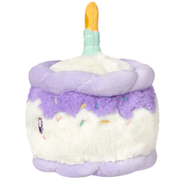 Side view of the Squishable Snacker Happy Birthday Cake soft toy showing lilac frosting and colourful sprinkles