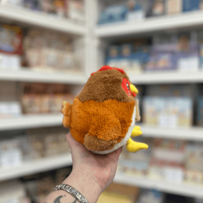 Squishable Snacker Hen plush toy side view held in hand in a shop