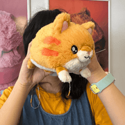 Squishable Snacker Kitty orange cat plush being held