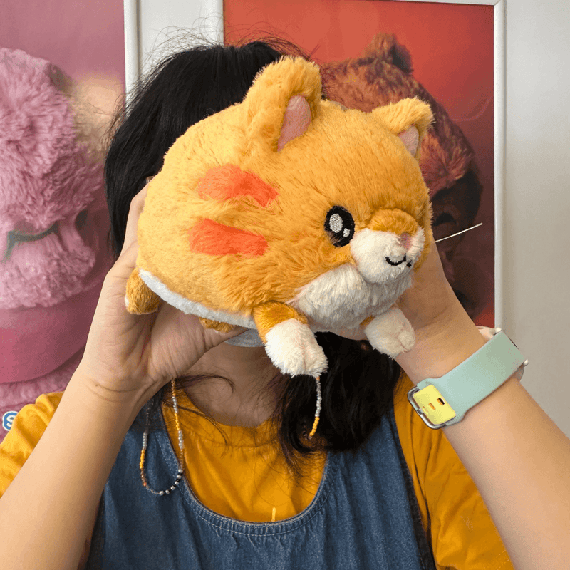 Squishable Snacker Kitty orange cat plush being held