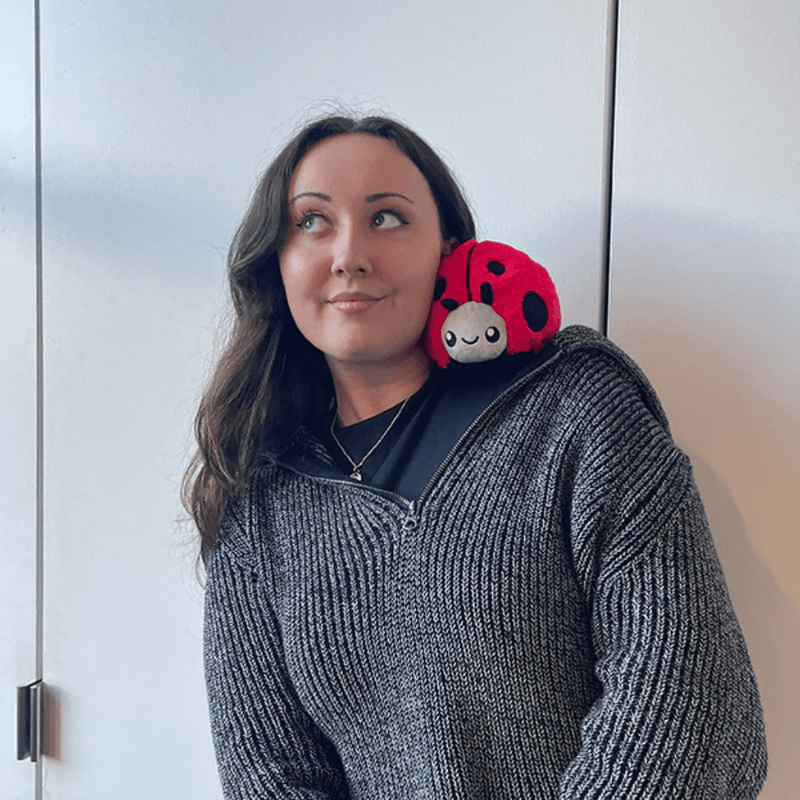 Person wearing Squishable Snacker Ladybug plush toy on shoulder