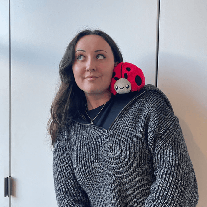 Person wearing Squishable Snacker Ladybug plush toy on shoulder