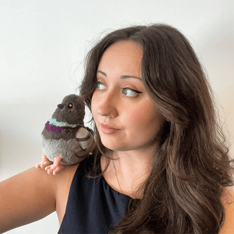 Woman holding the Squishable Snacker Pigeon plush toy on her shoulder