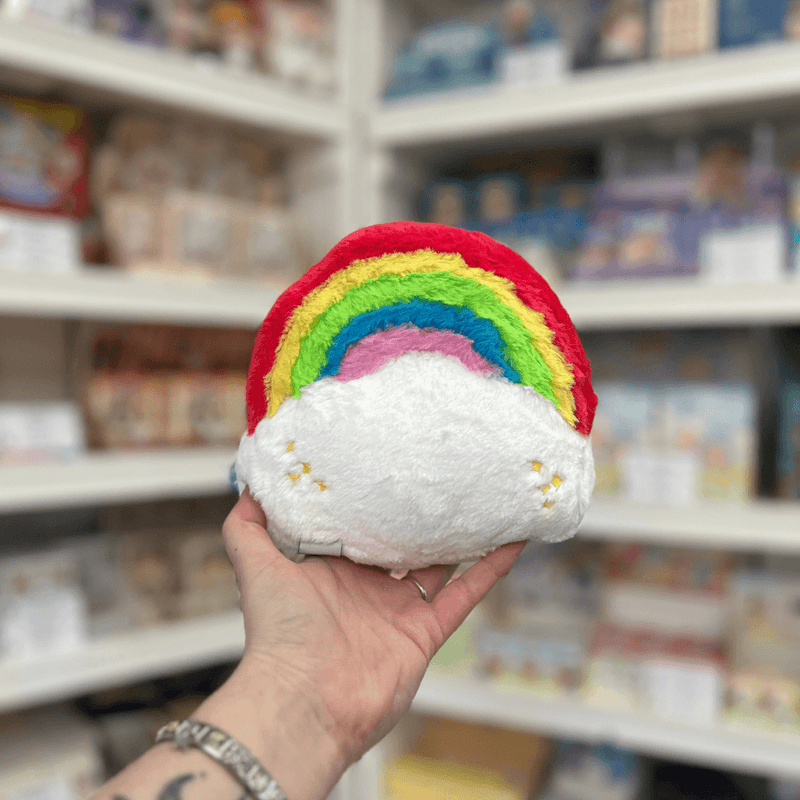 Squishable Snacker Rainbow plush toy back view held in hand in a shop