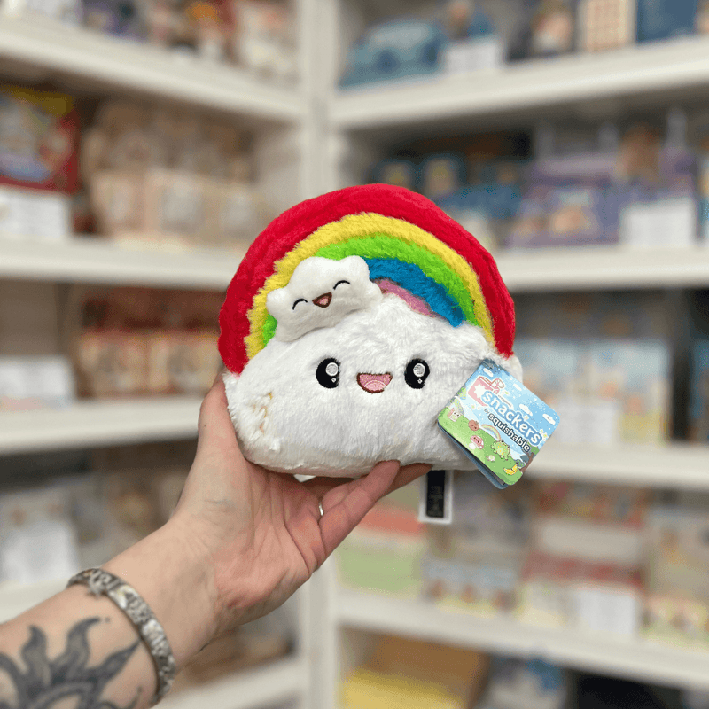 Squishable Snacker Rainbow plush toy front view held in hand in a shop