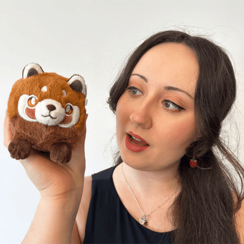Squishable Snacker Red Panda plush toy being held for size comparison