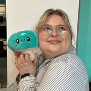 Person holding Squishable Snacker Turquoise Mushroom plush toy by their face