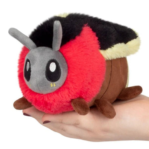 Palm-sized Squishable Snackers Firefly plush in a hand, red ruff and grey face.
