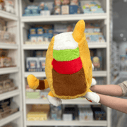 Squishable Taco Cat plush toy held in hands in a gift shop, side view showing taco shell and filling detail