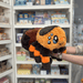 Squishable Tarantula plush toy held in hands in a gift shop, angled side view