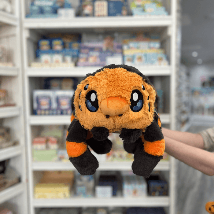 Squishable Tarantula plush toy held in hands in a gift shop, front view