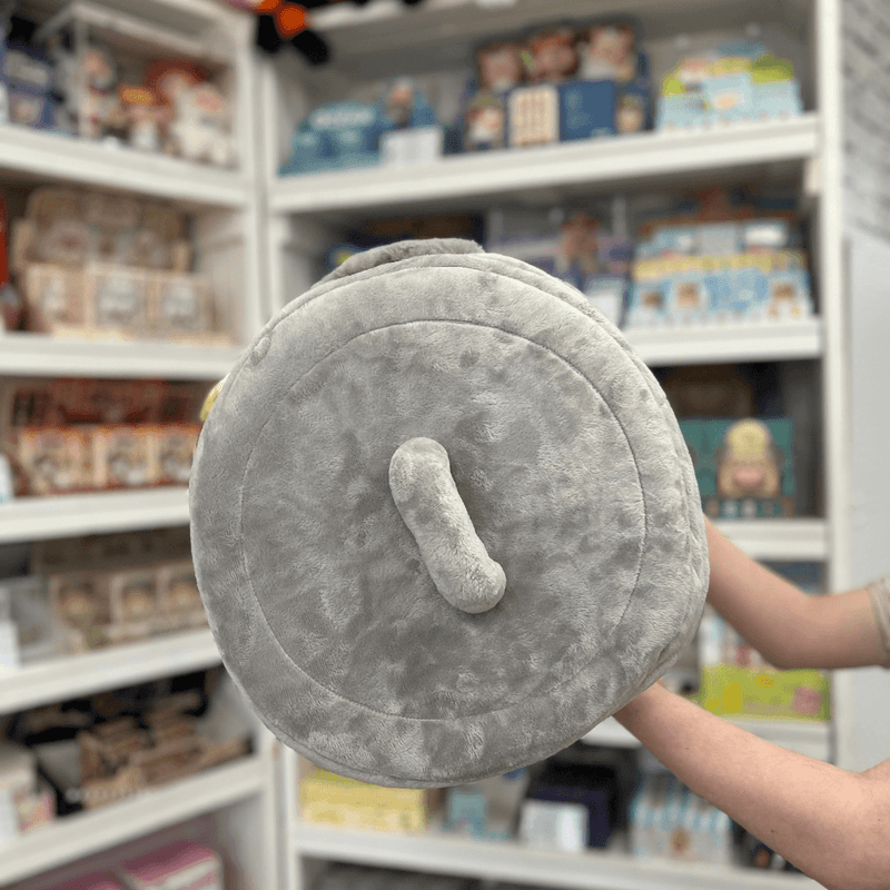 Squishable Trash Can plush toy held in hands in a gift shop, top view showing lid handle