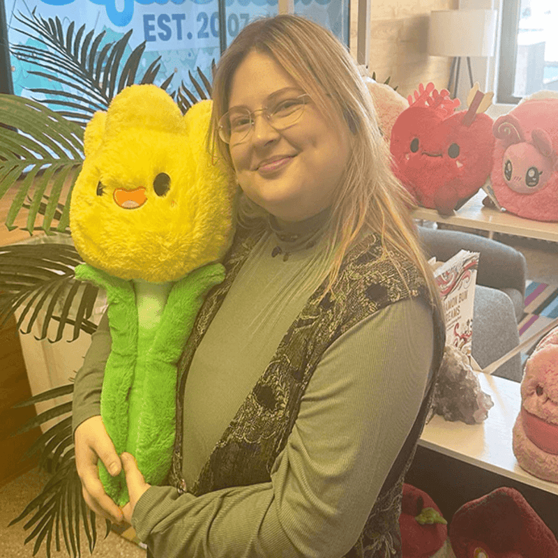 Person holding a large Squishable Tulip plush toy with yellow flower and green stem