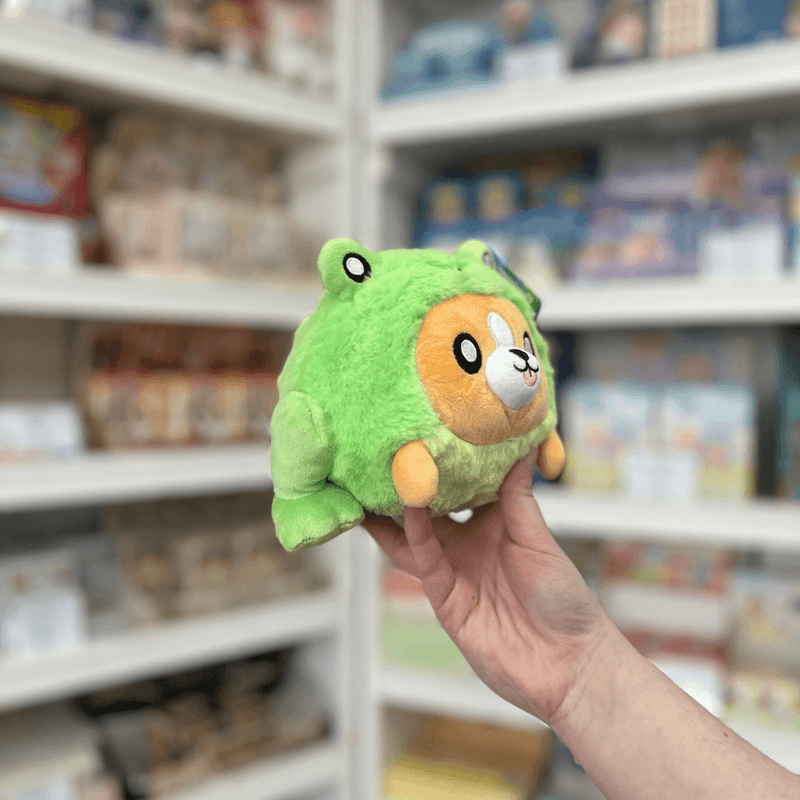 Squishable Undercover Snacker Corgi in Frog plush toy angled view held in hand in a shop