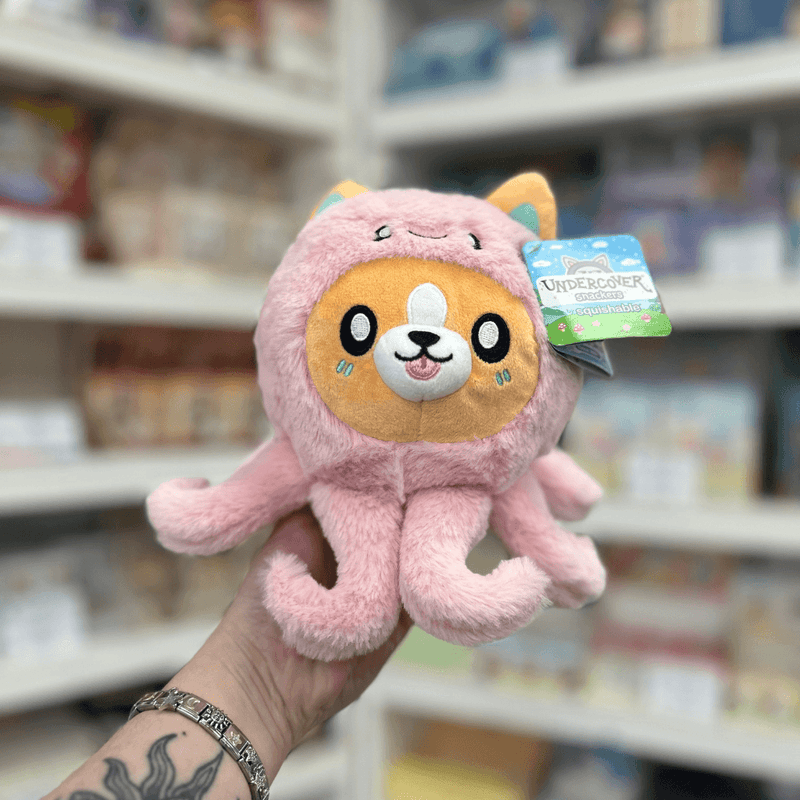 Squishable Undercover Snacker Corgi in Octopus plush toy front view held in hand in a shop