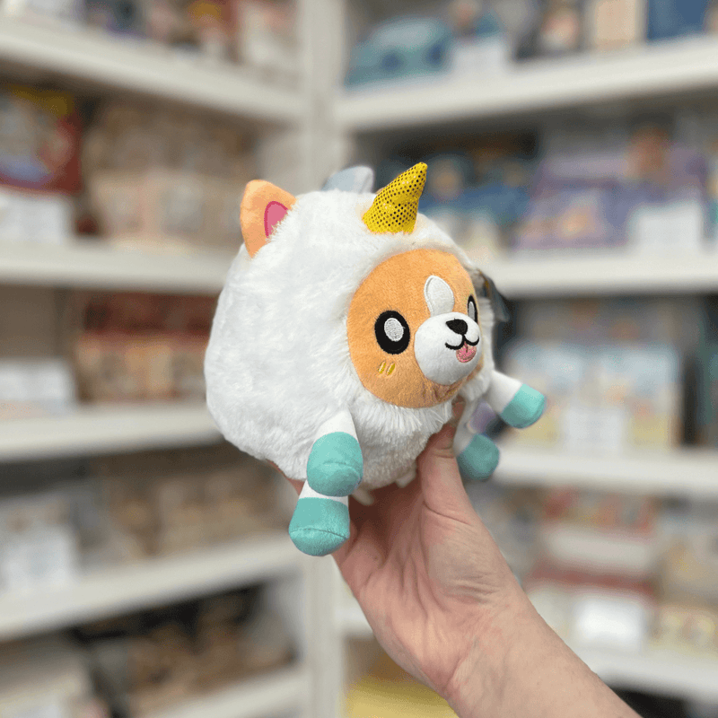 Squishable Undercover Snacker Corgi in Unicorn plush toy angled view held in hand in a shop