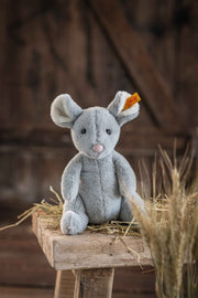 Lifestyle shot of Steiff Cheesy Mouse plush in barn setting on straw – Steiff bears gift idea