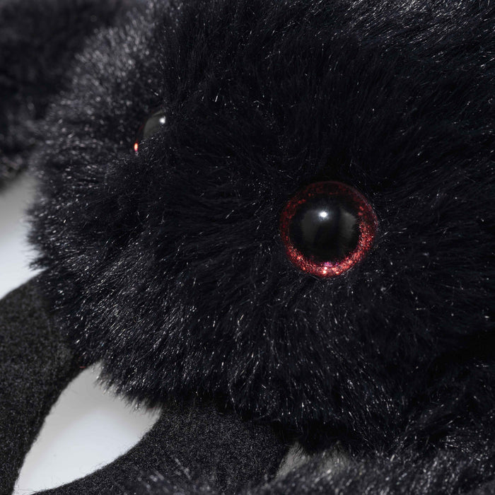 Close-up of plush spider showing glossy black eye with red sparkle ring