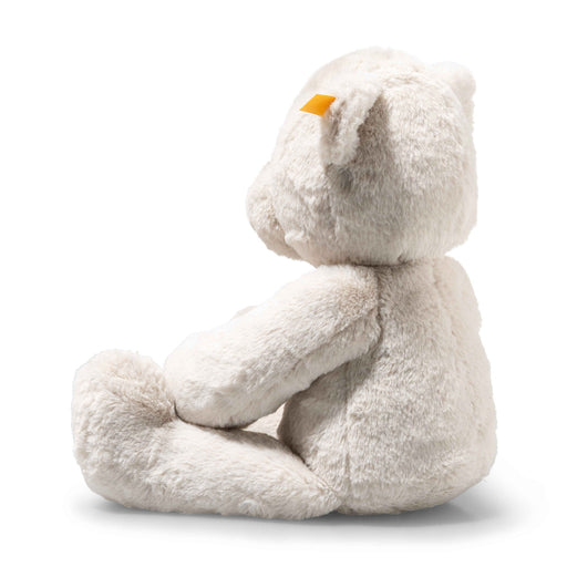 Side profile of Steiff Robby teddy bear in cream plush, yellow ear tag visible