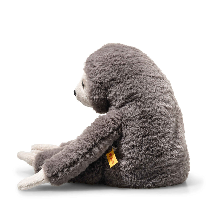 Side view of Steiff Sanny Sloth plush, long limbs and fluffy grey coat, yellow ear tag visible.
