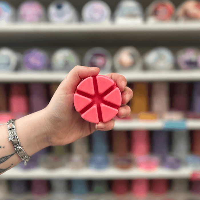 Strawberries and Cream wax melt segments held in hand with colourful wax melt display in the background