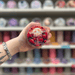 Strawberry Fields wax melt pot held in hand with colourful wax melt display in the background
