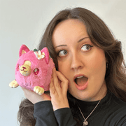 Person holding Squishable Alter Egos Strawberry Kitty Plush in pink with flower and leaf details