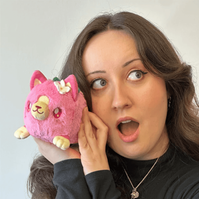 Person holding Squishable Alter Egos Strawberry Kitty Plush in pink with flower and leaf details