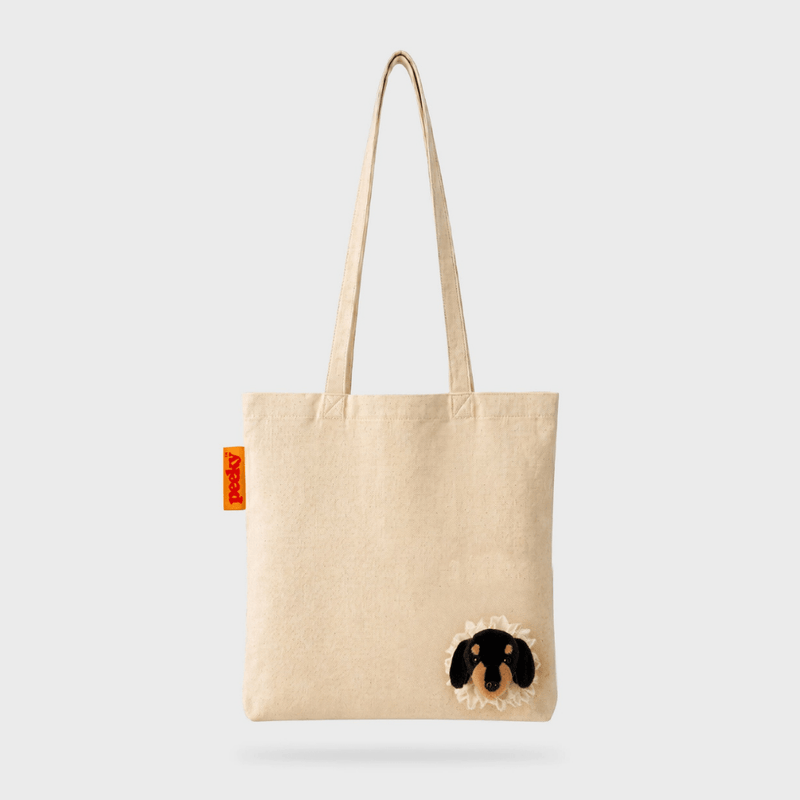 Full front view of the SUCK UK Peeky Dog natural cream cotton tote bag with long handles and a three-dimensional black-and-tan puppy head.