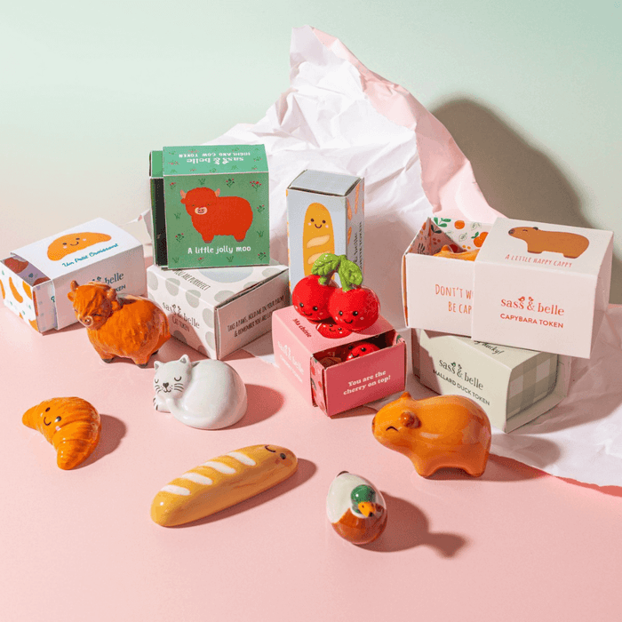 Sass & Belle Highland Cow pocket token shown with other pocket tokens and gift boxes on a pastel background