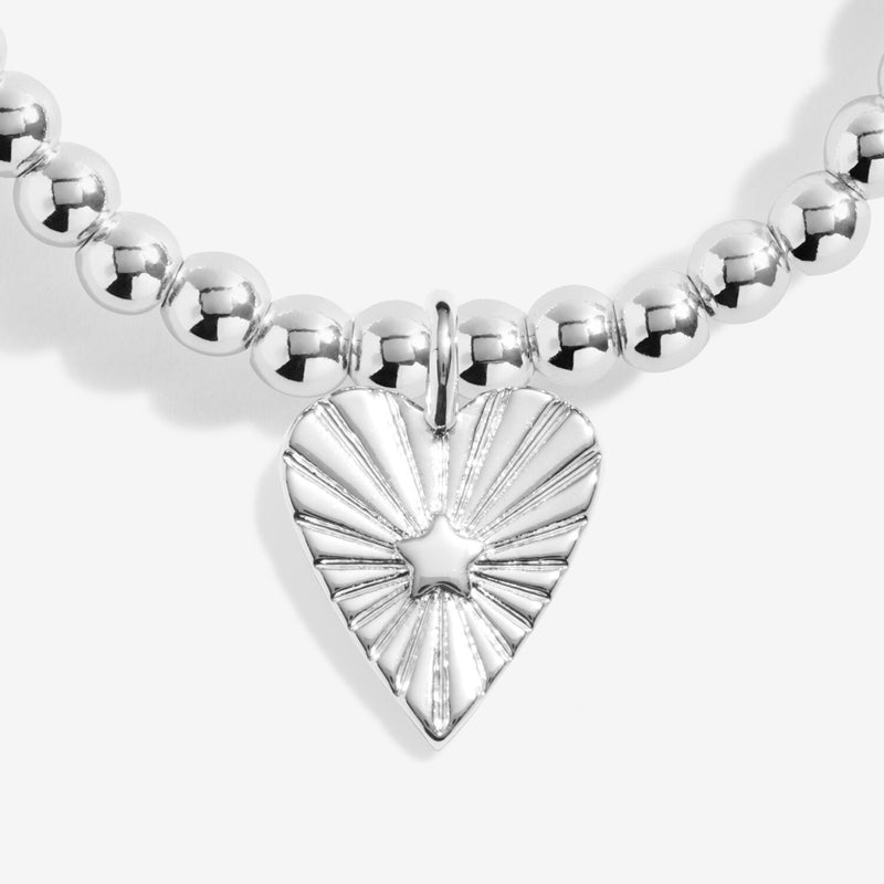 “Close‑up of sunburst heart charm with engraved rays and star detail”
